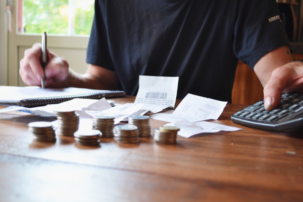 coins stacked on the table with man calculating bills in the background